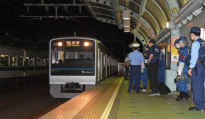 小田急線車内で6日、乗客が刃物で切られた事件で、ホームを調べる警察官ら＝2021年8月7日未明、東京都世田谷区（後方は、運転再開され、新たに運行される車両）