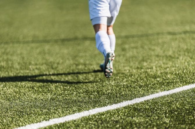 グリーングラスのピッチを走るサッカー選手