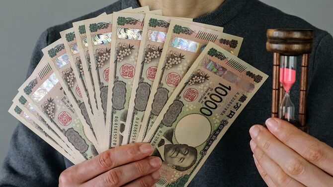 砂時計と紙幣の山を持つ人物