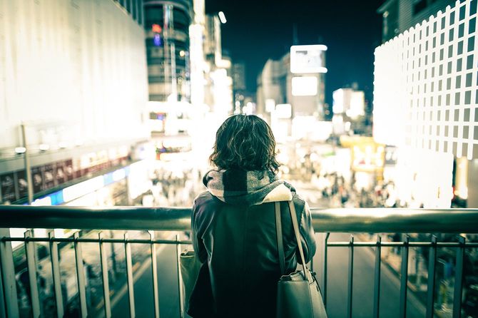 都会の夜景を眺めている若い女性