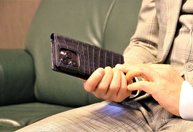 坂本氏のスマホケースは「GRAMAS Meister」。常に自社の最新商品を身に着け、使用感や改善点を次の商品開発に生かしているという