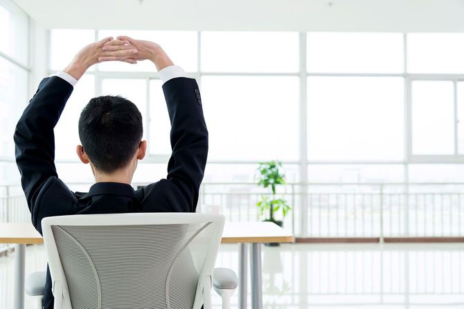 オフィスの椅子に座って伸びをする人