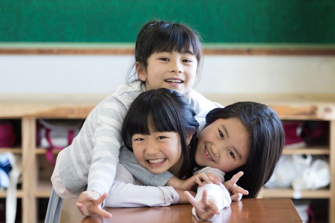 教室で仲良し3人組がカメラに向かってピースマーク