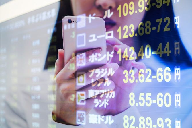 金融チャートとスマホを見つめる女性