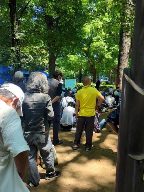 暑さに耐えながら炊き出しに並ぶ人々