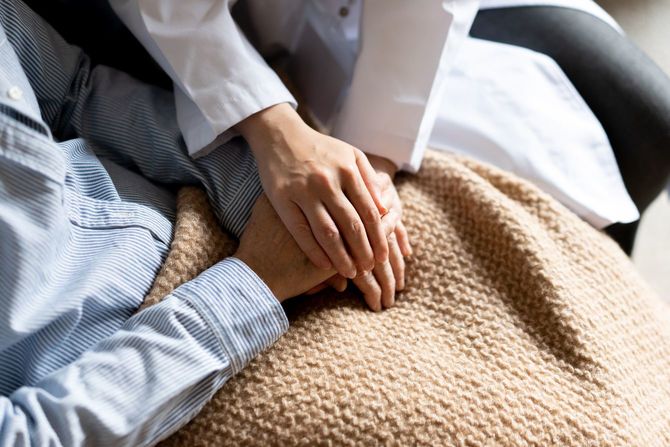シニアの手を取り、励ます医療従事者の手元