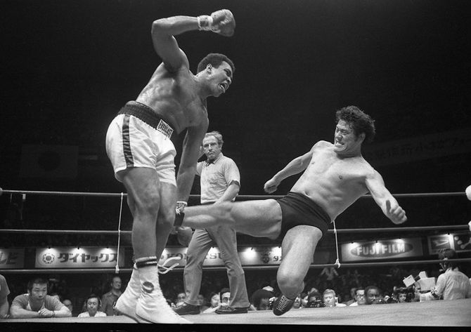 アントニオ猪木（右）がモハメド・アリにローキック（アリキック）を浴びせる（東京・日本武道館、1976年6月26日）