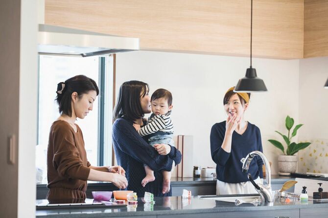 台所で話をする赤ちゃんを抱えた女性