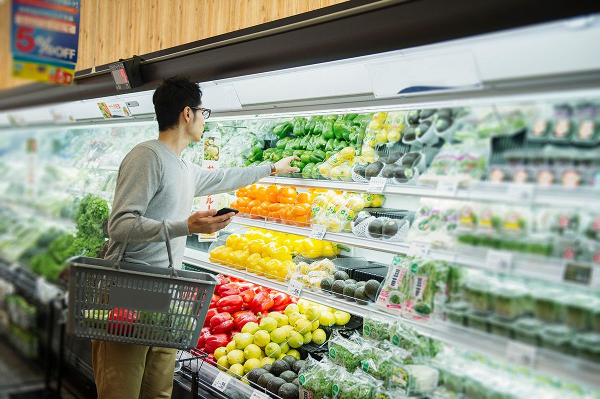 スーパーの野菜売り場で商品を選ぶ男性