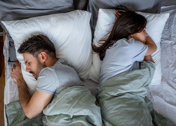 ベッドで口論した後、背中合わせに寝ている若いカップル
