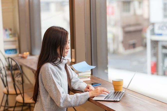 カフェでラップトップを見ている若い日本人女性