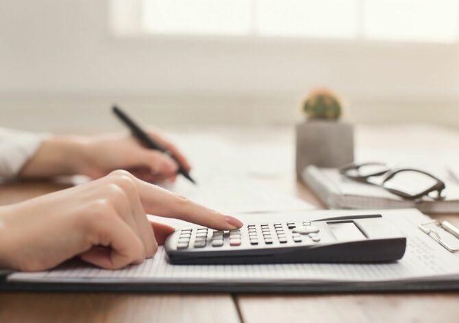 電卓で計算し文書に書く女性の手