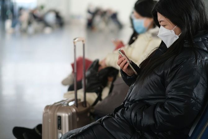 マスクをして空港のベンチに座っている人たち