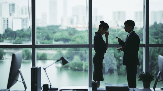 オフィスで上司に叱責される女性のシルエット