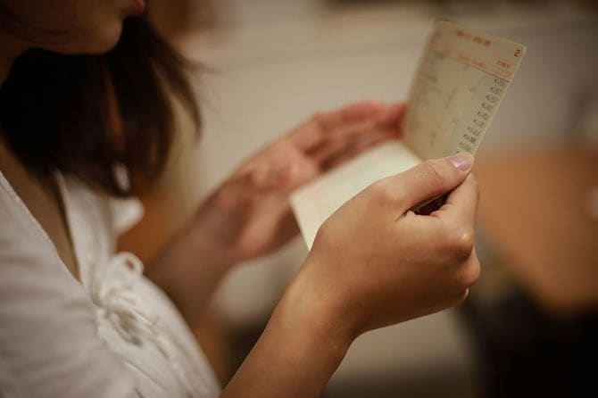 通帳を見て心配している女性