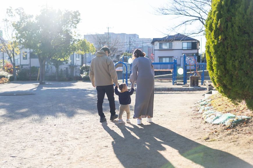 手をつないで公園を歩く親子