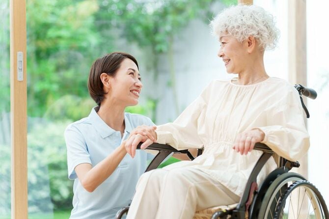 車椅子に乗る年配の女性と介護士