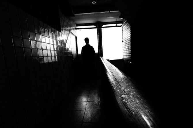 薄暗い建物の窓辺に立っている男性のシルエット