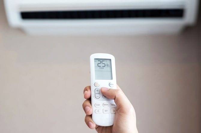 リモコンでエアコンの温度を25度に設定している手元