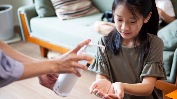 子供の手に消毒液を出す母親