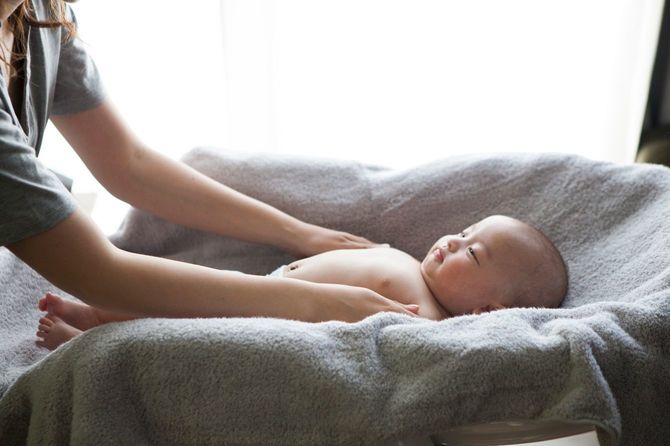 赤ちゃんの腕をやさしくなでる母親