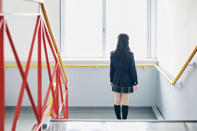 階段の踊り場に一人で立っている女子学生