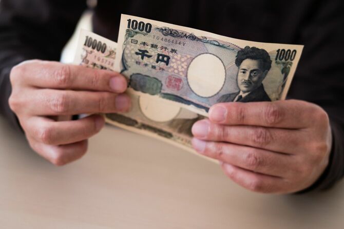一万円札と千円札を持つ男性の手元
