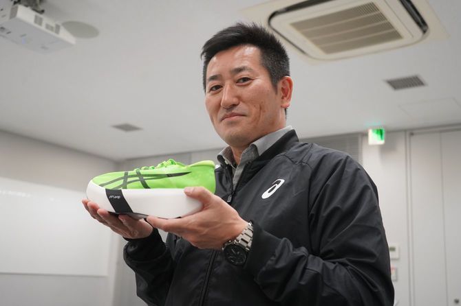 129gの超軽量シューズ「MASTERSPEED レイ」を持つ竹村さん。