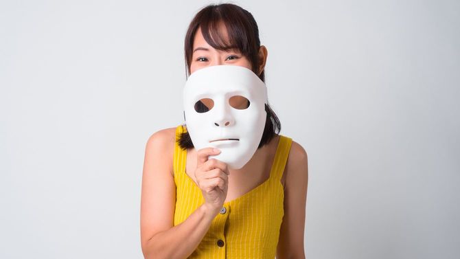 黄色いドレスを着て仮面を手にする女性