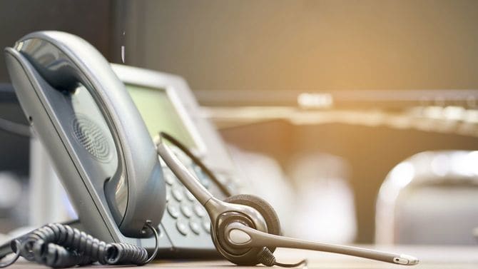 顧客サポートオフィスの机の上に電話とインカム