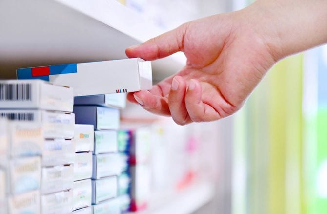 棚から薬品を取り出す薬剤師の手元