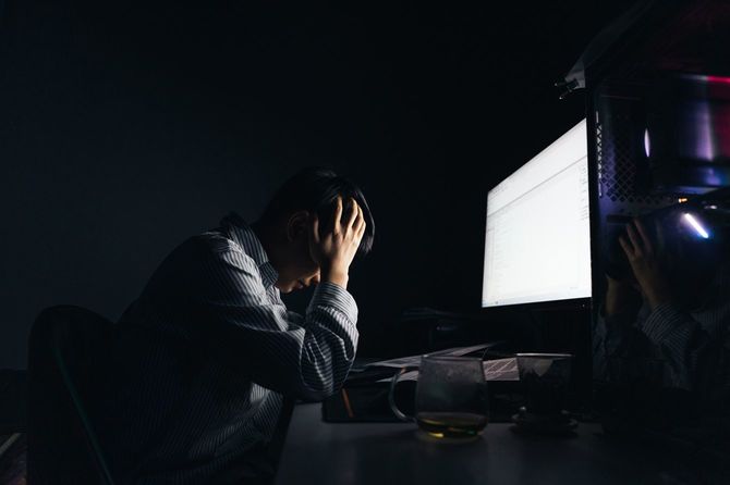 コンピューターの前で絶望する男性