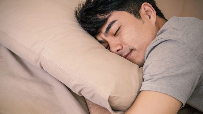 笑顔を浮かべながら腹臥位で眠る男性