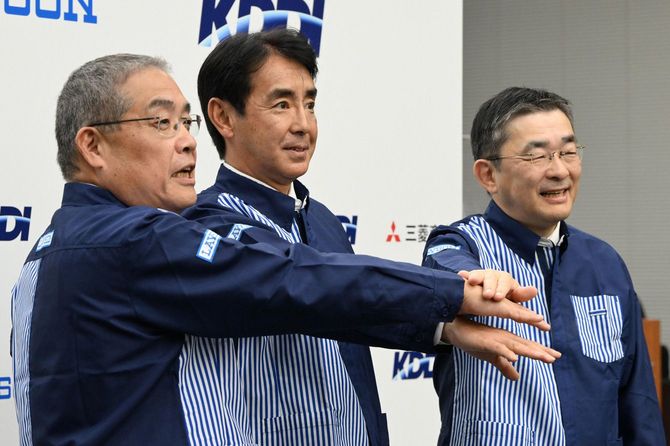 資本業務提携に関する記者会見を終え、ローソンのユニホームを着て手を合わせる（左から）三菱商事の中西勝也社長、ローソンの竹増貞信社長とKDDIの高橋誠社長