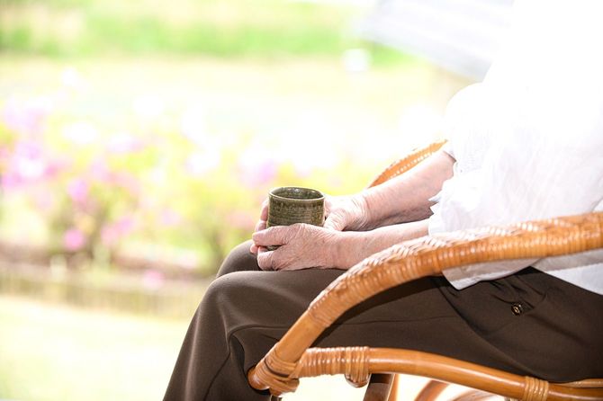 椅子に座ってお茶を飲む高齢者
