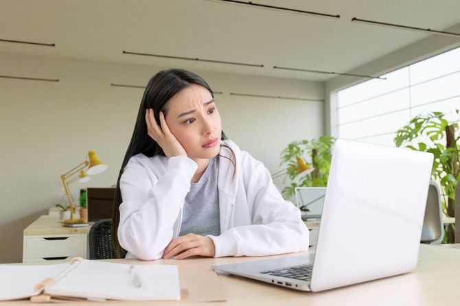 ノートパソコンの前で顔をしかめる女性