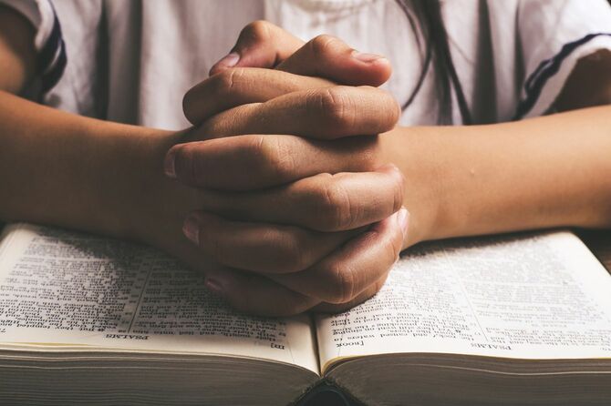 開いた聖書と祈る手