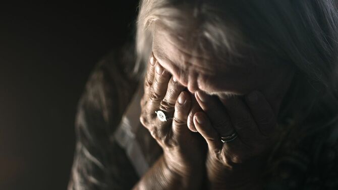 暗い部屋で泣く絶望的な老人