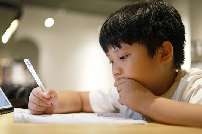 彼の机の上で男子生徒が数学の宿題をしている