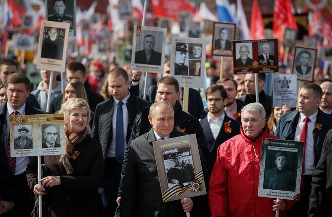 第二次世界大戦の犠牲になった人々の肖像画を掲げ、対ドイツ戦勝式典に出席するプーチン大統領＝5月9日、モスクワ