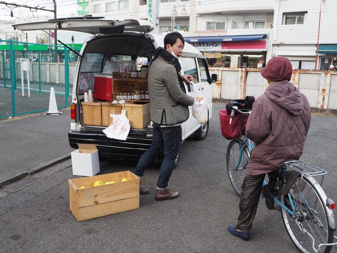 自転車のお客さんと白いバンの荷台の商品と片山さん