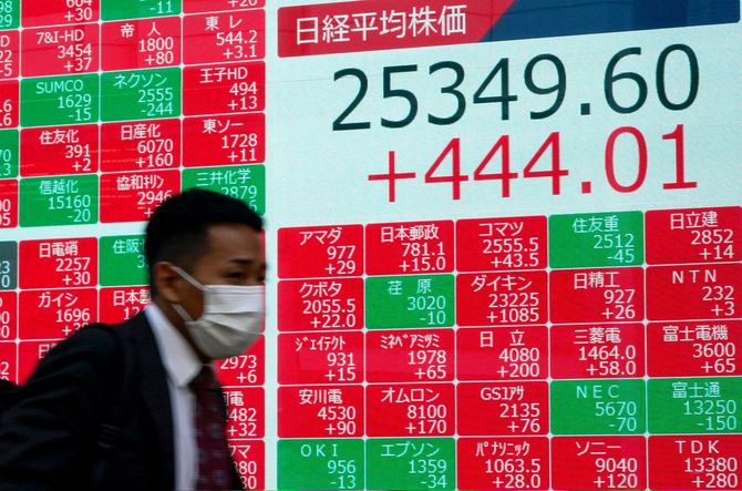 東京の日経平均株価の終値を示すディスプレイの前を歩く歩行者＝2020年11月11日