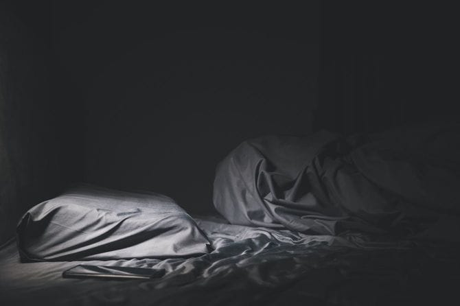 暗い部屋でベッドメイクされていない人のいないベッド