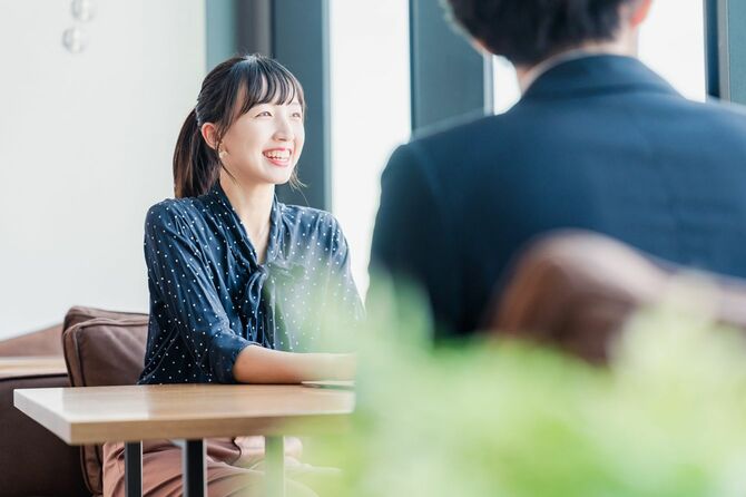 笑顔で話す女性と話を聞いている男性の後ろ姿