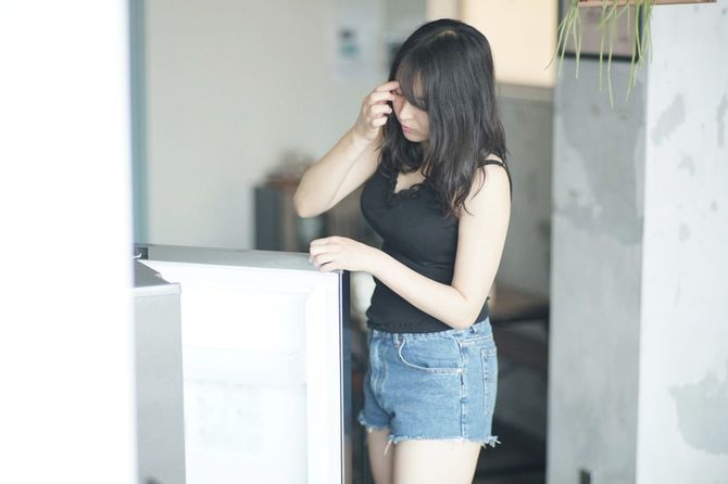 冷蔵庫の中を見る若い女性