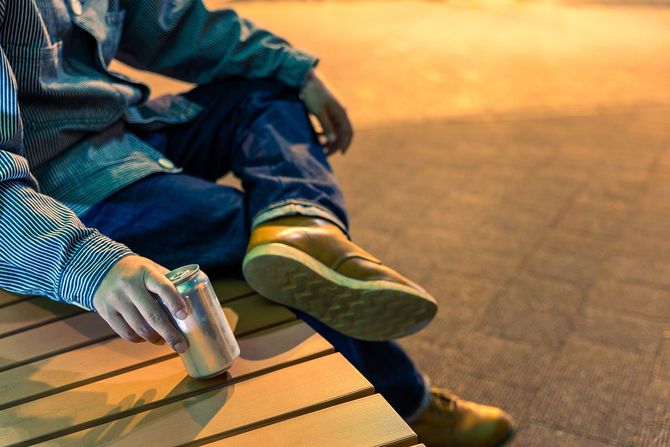 路上で缶ビールを飲む若者