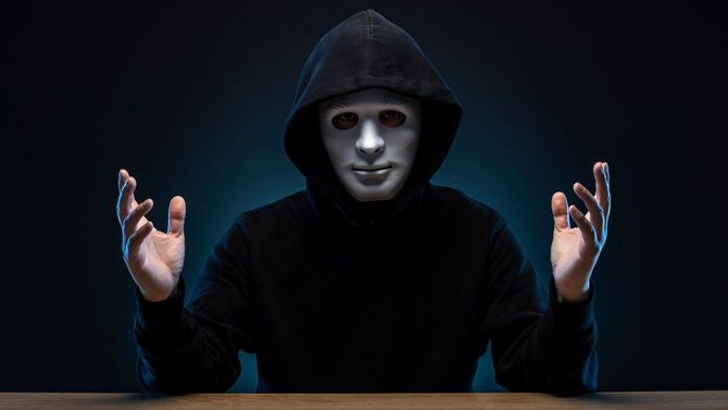 黒のパーカーを着て白い面をつけた男性