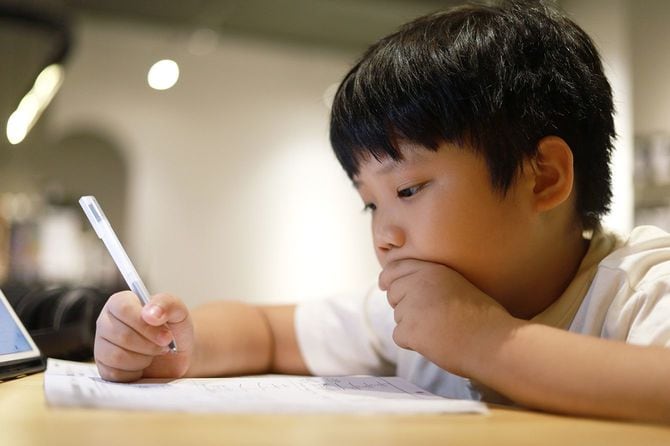 彼の机の上で男子生徒が数学の宿題をしている