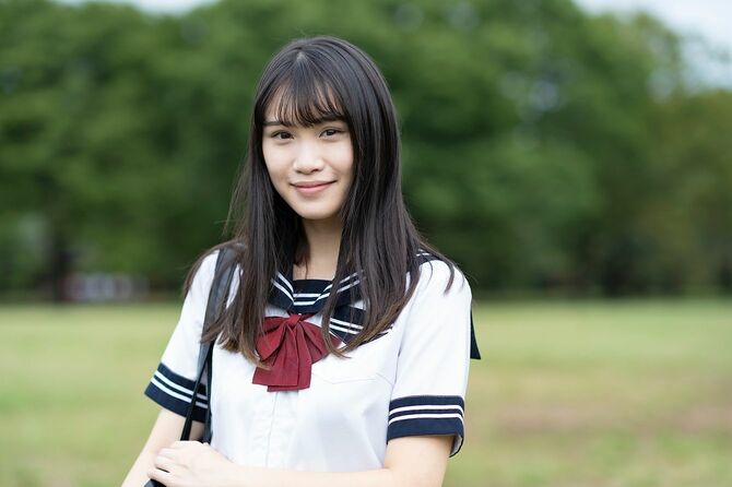 屋外で制服を着て微笑むアジアの女子高校生