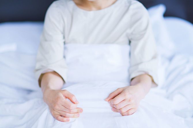 ベッドで起き上った状態の女性